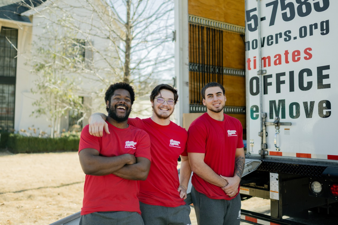 Three movers standing in front of a Motivated Movers Birmingham truck ready to serve